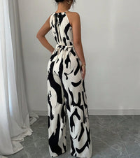 Person wearing a black and white patterned jumpsuit in a room with white curtains and gray floor.
