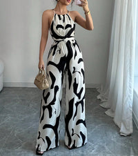 Woman wearing a black and white patterned jumpsuit in a room with a gray floor and white curtains.