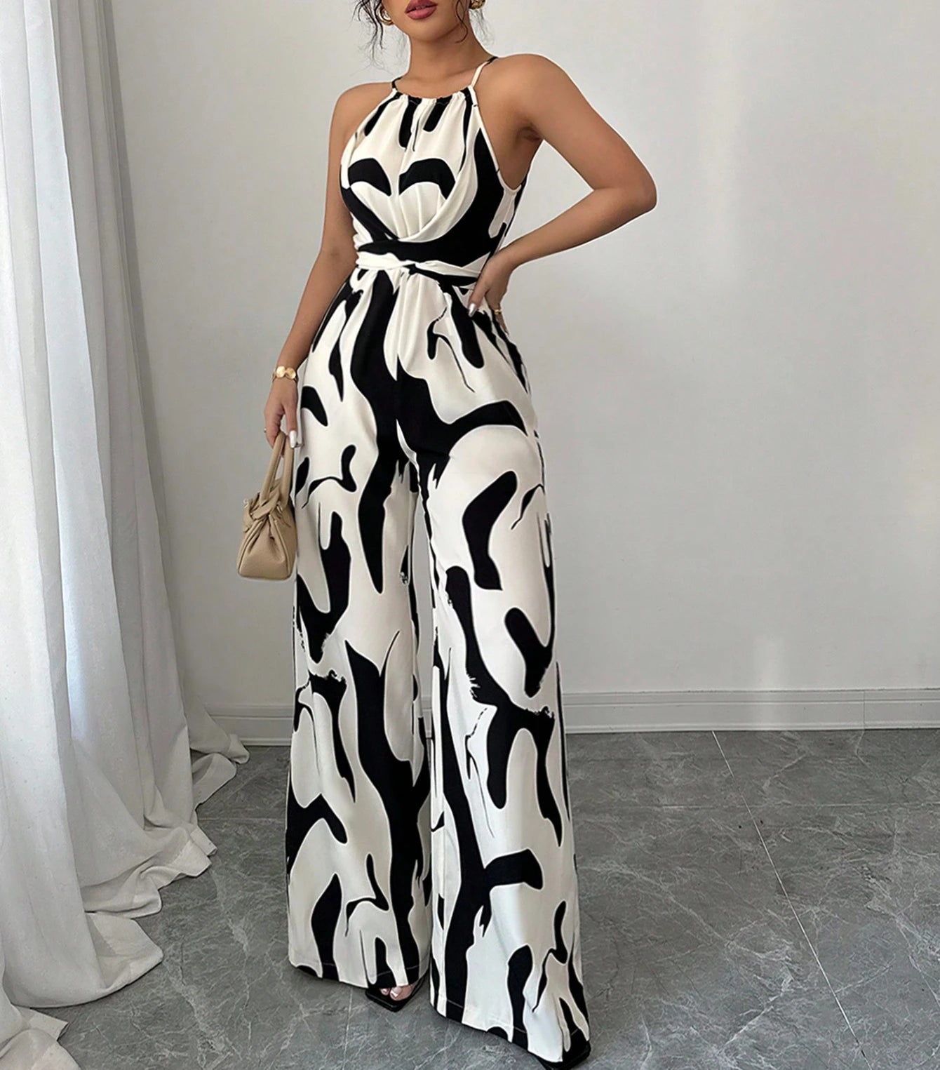 Woman wearing a black and white patterned jumpsuit in an indoor setting.