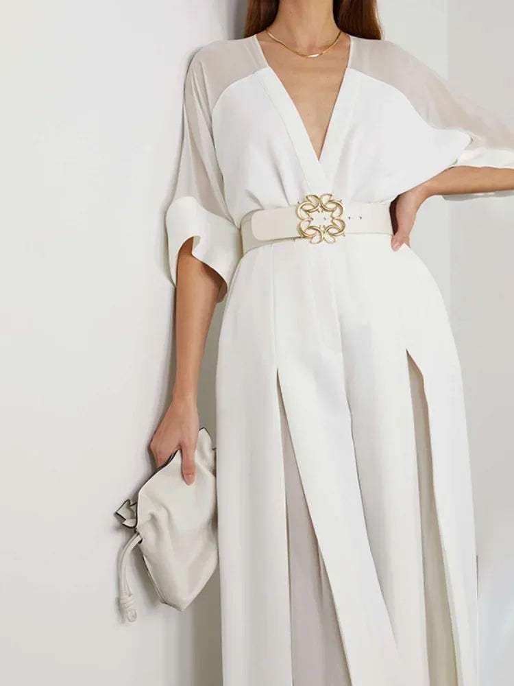 White outfit with a belt and clutch on a plain background