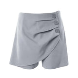 A pair of high-waisted, asymmetric cut women's summer shorts in a light solid color, featuring a button detail on the side.