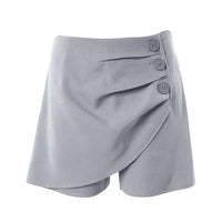 A pair of high-waisted, asymmetric cut women's summer shorts in a light solid color, featuring a button detail on the side.