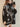 A woman wearing a black oversized autumn pullover knitted top with a turtleneck design and geometric patterns.